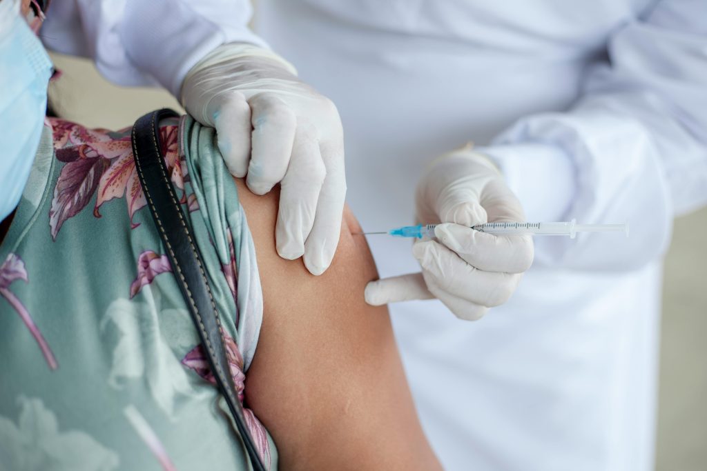 pexels-photo-8488619-8488619 Close-up of a healthcare professional giving a vaccine shot to a patient wearing a mask.